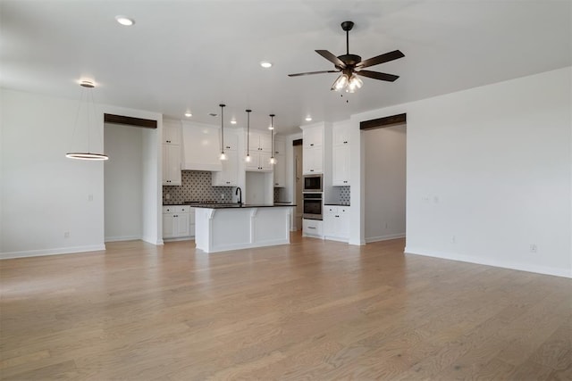 unfurnished living room featuring light hardwood / wood-style floors, ceiling fan, and sink