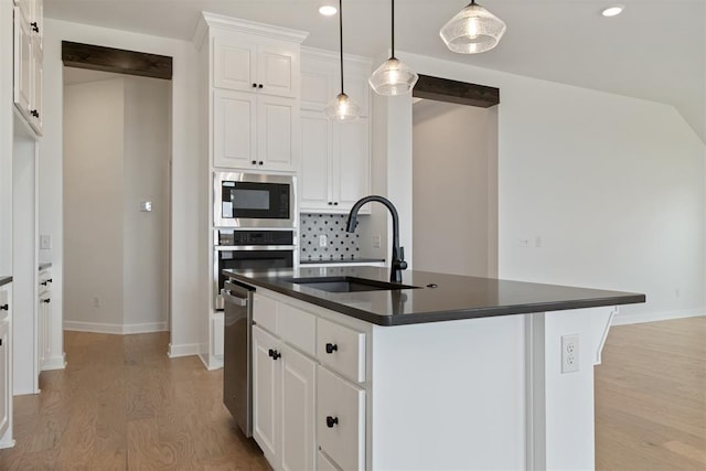 kitchen with white cabinetry, sink, and a kitchen island with sink