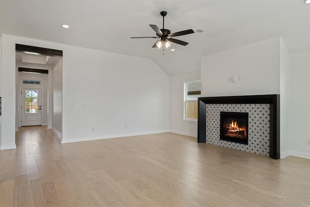 unfurnished living room with a fireplace, light wood-type flooring, ceiling fan, and lofted ceiling