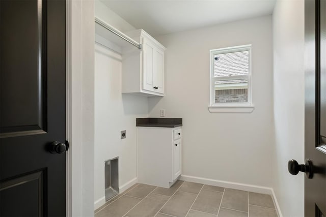 laundry area with hookup for an electric dryer, light tile patterned floors, and cabinets