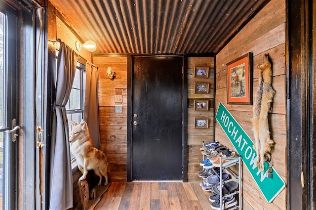 entrance foyer with hardwood / wood-style flooring, wood ceiling, and wooden walls