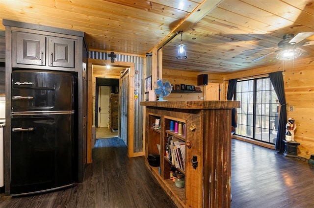 kitchen with black refrigerator, wooden walls, dark wood-type flooring, and wood ceiling