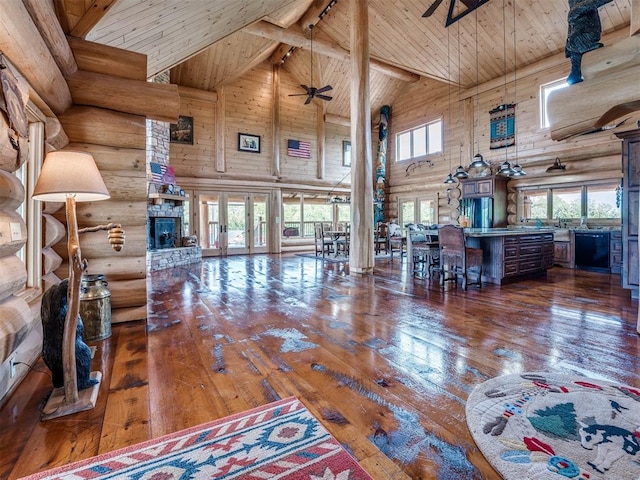 living room with dark hardwood / wood-style flooring, ceiling fan, rustic walls, high vaulted ceiling, and wooden ceiling