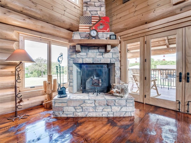 living room with wood-type flooring, a fireplace, a towering ceiling, and log walls