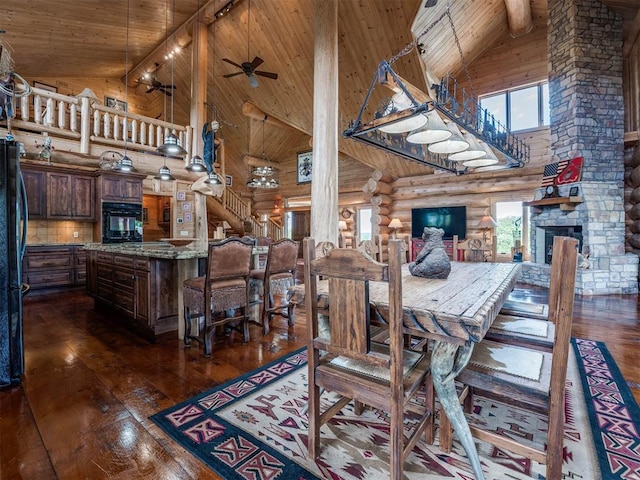 dining room with a stone fireplace, wooden ceiling, dark hardwood / wood-style flooring, log walls, and high vaulted ceiling