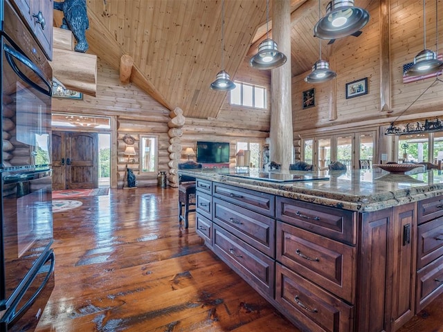 kitchen with dark hardwood / wood-style floors, pendant lighting, rustic walls, light stone countertops, and high vaulted ceiling