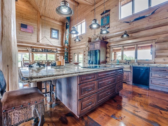 kitchen with a kitchen bar, decorative light fixtures, high vaulted ceiling, rustic walls, and black appliances