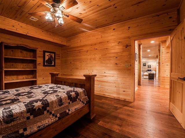 bedroom with ceiling fan, wooden ceiling, hardwood / wood-style flooring, and wooden walls