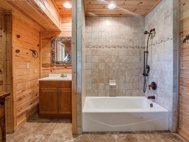 bathroom with tiled shower / bath combo, wood ceiling, vanity, and wood walls