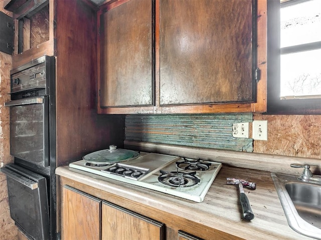 kitchen featuring white gas cooktop, oven, tasteful backsplash, and sink