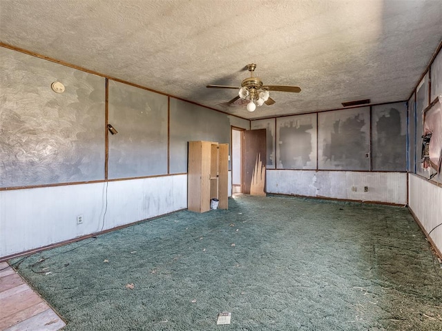 carpeted spare room featuring a textured ceiling and ceiling fan