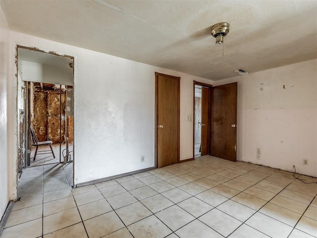 empty room with light tile patterned floors and a textured ceiling