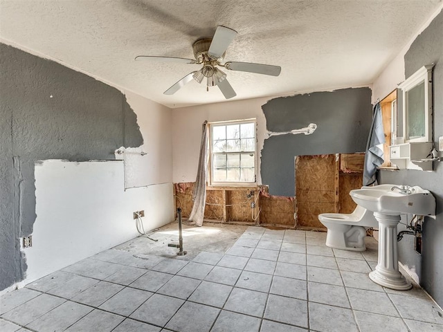 interior space with a textured ceiling and ceiling fan