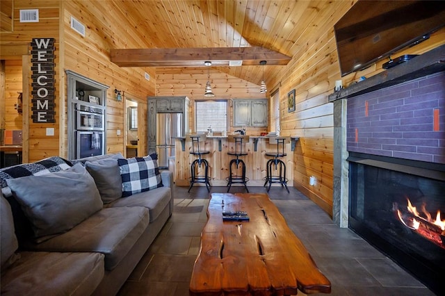 tiled living room with vaulted ceiling with beams, wooden walls, a fireplace, and wooden ceiling