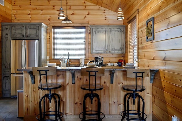 kitchen with hanging light fixtures, a kitchen breakfast bar, stainless steel fridge, lofted ceiling, and a kitchen island