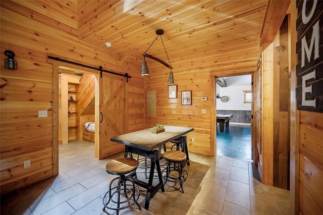 dining room with a barn door, light tile patterned floors, wooden ceiling, and wooden walls