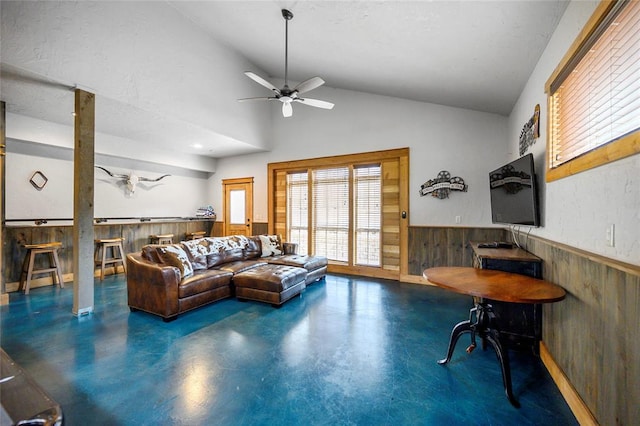 living room featuring ceiling fan, wood walls, and high vaulted ceiling