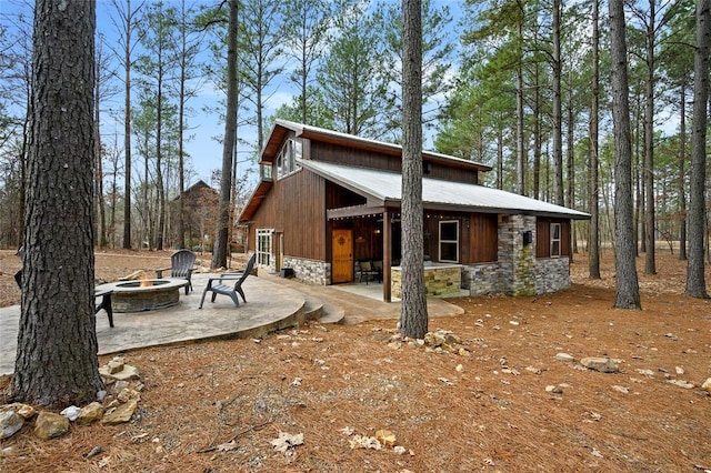 44 Blue Ivey Cir, Broken Bow, OK 74728 - back of property with an outdoor fire pit, stone siding, a patio area, and a metal roof