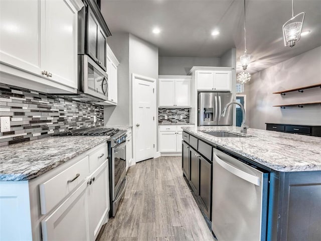 kitchen featuring stainless steel appliances, sink, pendant lighting, light hardwood / wood-style flooring, and white cabinetry