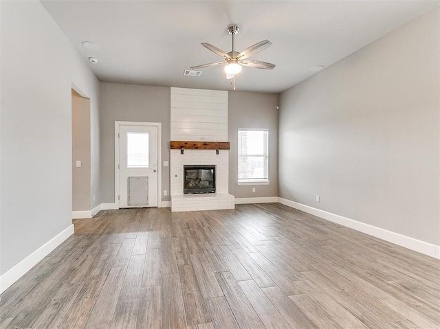 unfurnished living room featuring ceiling fan, light wood-type flooring, and a fireplace