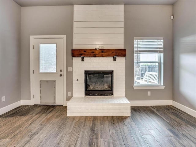 unfurnished living room featuring dark hardwood / wood-style floors and a brick fireplace