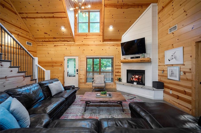 living room featuring an inviting chandelier, high vaulted ceiling, wood ceiling, and wood walls