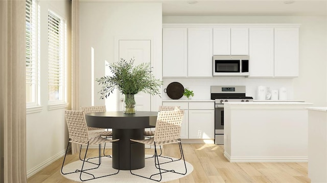 kitchen featuring stainless steel range, decorative backsplash, light hardwood / wood-style flooring, and white cabinetry