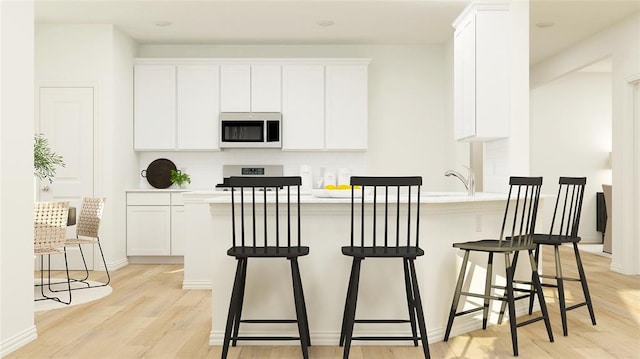 kitchen featuring light hardwood / wood-style floors, white cabinetry, and a breakfast bar area