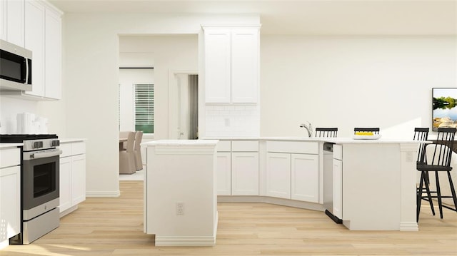 kitchen with a center island, light wood-type flooring, white cabinetry, and appliances with stainless steel finishes