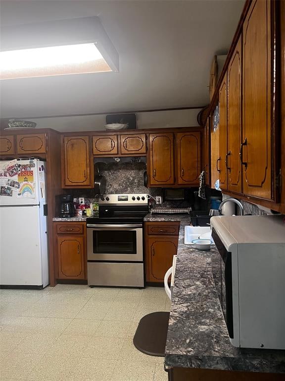 kitchen with white fridge, electric stove, backsplash, and dark stone counters