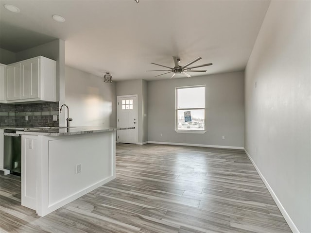 kitchen with sink, light hardwood / wood-style flooring, ceiling fan, white cabinetry, and tasteful backsplash