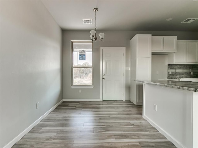 kitchen with visible vents, backsplash, baseboards, and white cabinetry