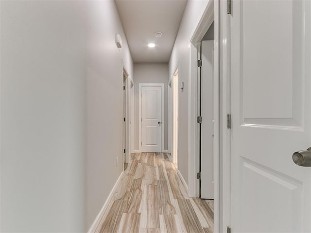 corridor with light wood-type flooring and baseboards