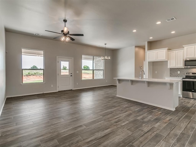 kitchen with white cabinets, ceiling fan with notable chandelier, dark hardwood / wood-style flooring, and appliances with stainless steel finishes