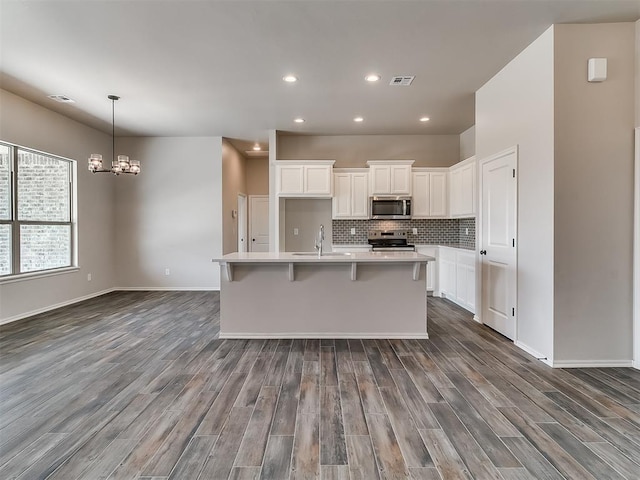 kitchen featuring a center island with sink, dark hardwood / wood-style floors, white cabinetry, and appliances with stainless steel finishes