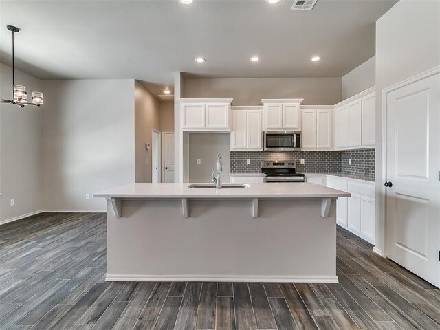 kitchen featuring a center island with sink, sink, stainless steel appliances, and dark wood-type flooring