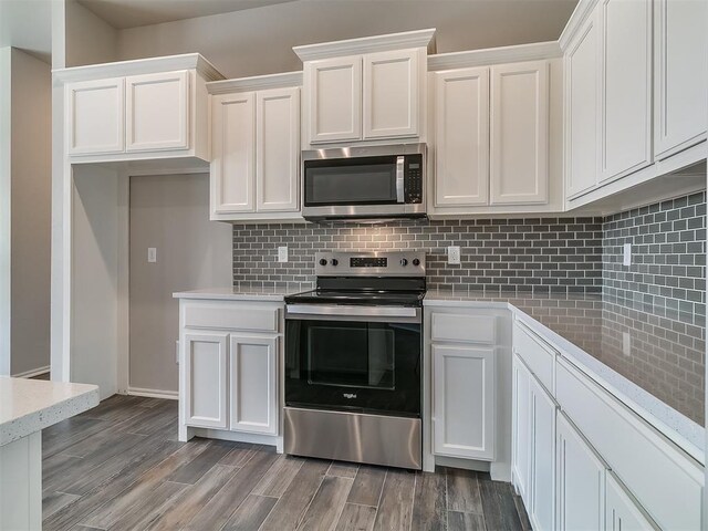 kitchen featuring tasteful backsplash, white cabinetry, stainless steel appliances, and wood-type flooring