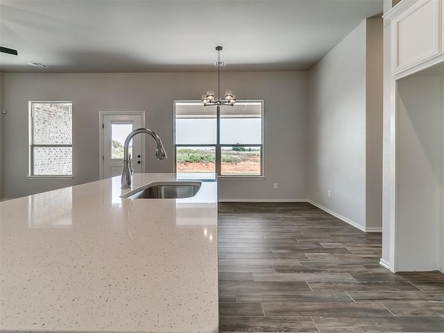 kitchen featuring light stone countertops, dark hardwood / wood-style flooring, sink, decorative light fixtures, and an inviting chandelier