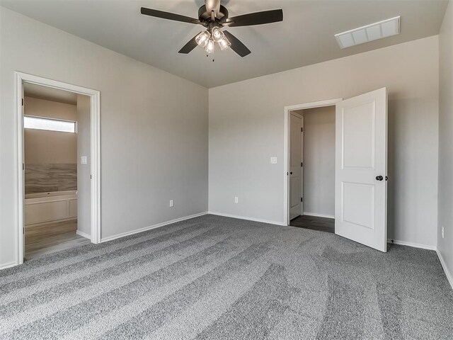 unfurnished bedroom featuring connected bathroom, ceiling fan, and dark colored carpet