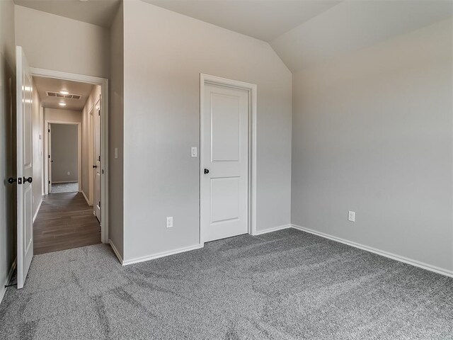 unfurnished bedroom featuring carpet and vaulted ceiling