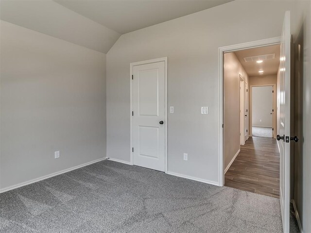 empty room with dark wood-type flooring and vaulted ceiling