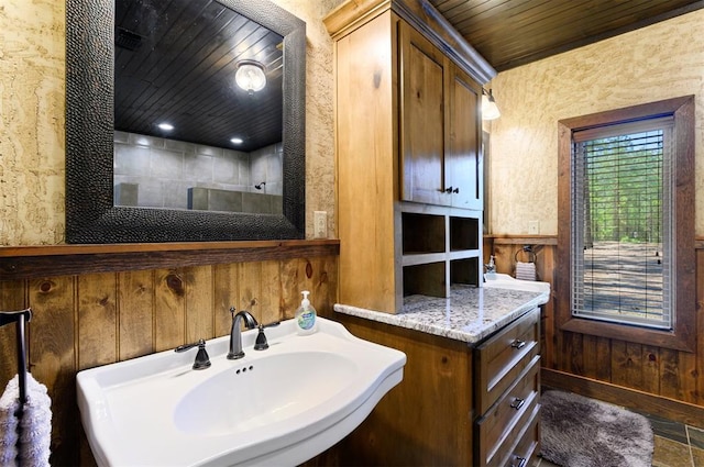 bathroom featuring wood walls, sink, and wooden ceiling