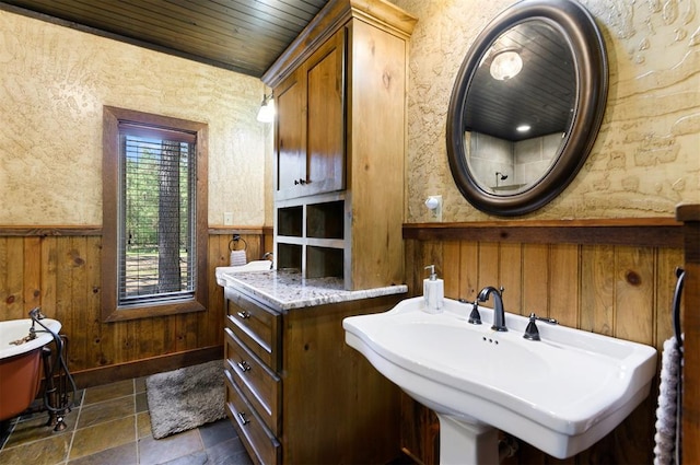 bathroom with sink, wood ceiling, and wood walls