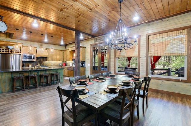 dining room with wooden ceiling, dark wood-type flooring, wooden walls, and an inviting chandelier