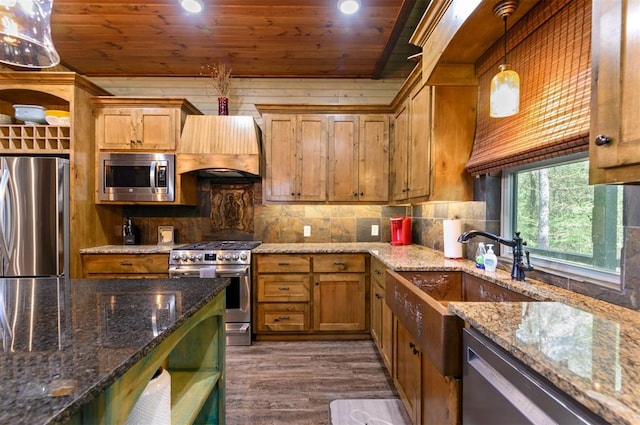 kitchen with hanging light fixtures, premium range hood, appliances with stainless steel finishes, and dark stone counters