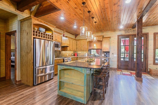 kitchen featuring wooden walls, a center island, dark hardwood / wood-style flooring, and appliances with stainless steel finishes