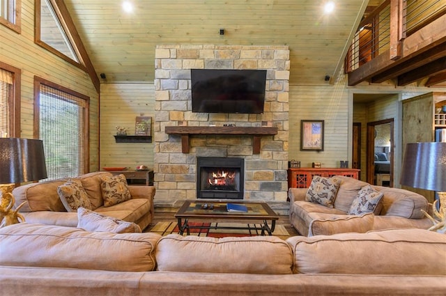 living room featuring wooden walls, a stone fireplace, wooden ceiling, and high vaulted ceiling