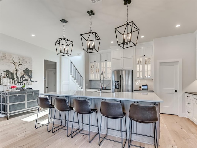 kitchen with a large island with sink, white cabinetry, and stainless steel refrigerator with ice dispenser