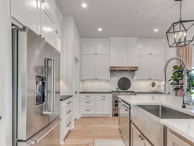 kitchen with light stone countertops, an inviting chandelier, light hardwood / wood-style floors, white cabinets, and high end appliances