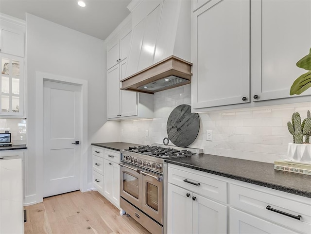 kitchen with white cabinetry, custom range hood, range with two ovens, and light wood-type flooring